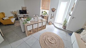 Ein Wohnzimmer mit einer Couch, einem Couchtisch, einem Fernseher und einem Bücherregal.