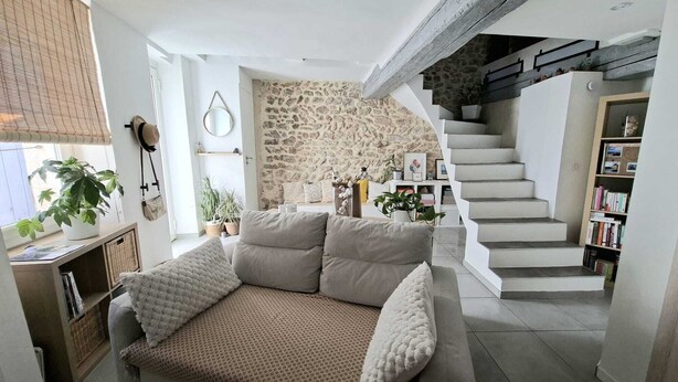 Ein Wohnzimmer mit einer Couch, einer Treppe und einer Steinwand.