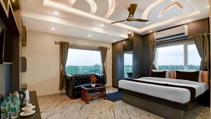 Ein modernes Hotelzimmer mit Bett, Sofa, Couchtisch und Blick auf die Stadt.