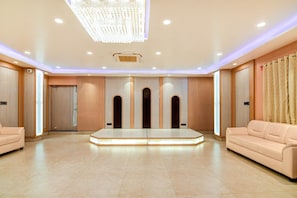 Een ruime hotellobby met een centraal zithoek, ingebouwde verlichting en een grote kroonluchter.