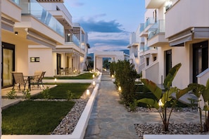 Um edifício residencial moderno com um caminho de pedra, área de estar externa e paisagismo bem cuidado.