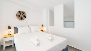 Hotelkamer met een bed, twee nachtkastjes, een wandlamp, een ronde wanddecoratie van gevlochten materiaal en een raam.