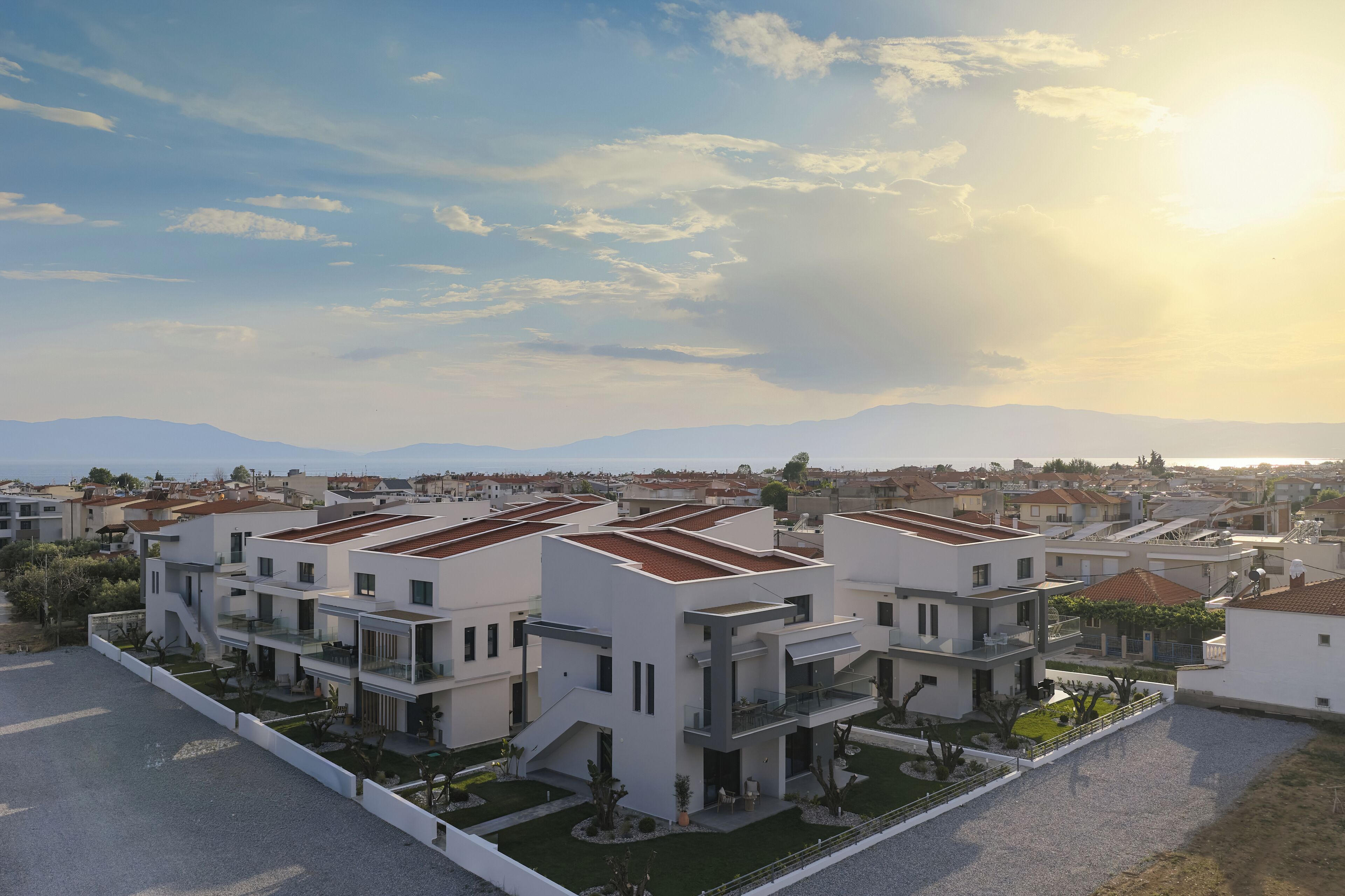 Un moderno complejo residencial con varias edificaciones de dos pisos, techos planos y un jardín bien cuidado.