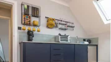 Uma cozinha com forno embutido, cafeteira e torradeira. Há armários e uma janela acima da pia.