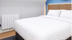 Een moderne slaapkamer met een groot bed, een radiator en een blauwe accentmuur.