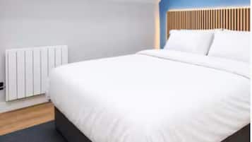 Quarto moderno com uma cama grande, um radiador e uma parede azul de destaque.