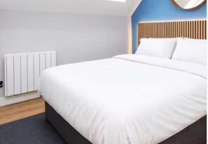 A modern bedroom with a large bed, a radiator, and a blue accent wall. - Central 1-bed Apartment, Sleeps 3 Near Parking (Bournemouth)