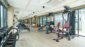 A gym with various exercise equipment, large windows, and a ceiling fan. - Best for Digital Nomad-1 BR Apt close to Surin Beach (Tambon Choeng Thale)