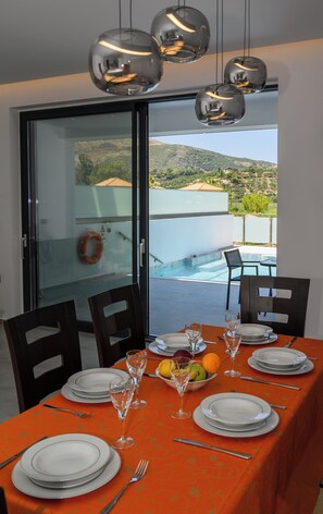 Ein Essbereich mit Tisch für vier Personen, mit Blick auf einen Pool und eine Berglandschaft.