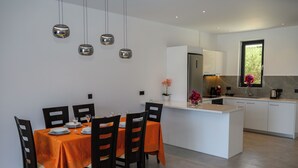 Una cucina moderna con isola centrale, zona pranzo con tavolo apparecchiato per quattro e illuminazione a sospensione.