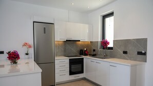 Una cucina moderna con mobili bianchi, un frigorifero in acciaio inossidabile, un forno e una finestra vista.