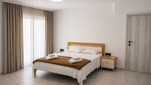 A hotel room with a bed, bedside tables, a wardrobe, and a large window with curtains. - Herodotos Residence–Peaceful Stay Near Keri Beach (Keri)