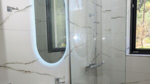 A modern bathroom with a glass-enclosed shower, a white sink with a marble countertop, and a large mirror with a circular frame. - Herodotos Residence–Peaceful Stay Near Keri Beach (Keri)