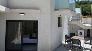 A modern building with a balcony, a sliding glass door entrance, outdoor seating, and a washing machine. - Herodotos Residence–Peaceful Stay Near Keri Beach (Keri)