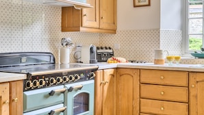 A kitchen with a vintage stove, wooden cabinets, and a window with a view. - Piddlehinton Coach House - Piddlehinton, Dorchester, sleeps 6 guests (Piddlehinton)