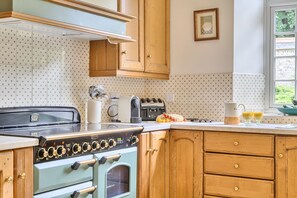 A kitchen with a vintage stove, wooden cabinets, and a window with a view. - Piddlehinton Coach House - Piddlehinton, Dorchester, sleeps 6 guests (Piddlehinton)