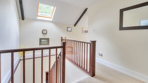 A staircase with wooden railings, a small window, and a wall-mounted clock. - Piddlehinton Coach House - Piddlehinton, Dorchester, sleeps 6 guests (Piddlehinton)