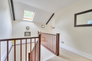 A staircase with wooden railings, a small window, and a wall-mounted clock. - Piddlehinton Coach House - Piddlehinton, Dorchester, sleeps 6 guests (Piddlehinton)