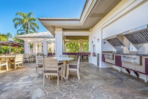 Eine Terrasss mit Steinbelag, Grillstation und Sitzgelegenheiten.
