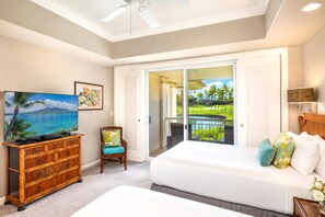A bedroom with a bed, a dresser, a chair, a television, and a sliding glass door leading to a balcony with a view of a golf course.