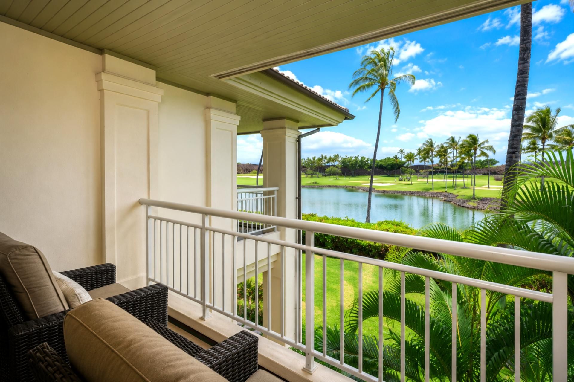 A balcony with a view of a golf course and a body of water.