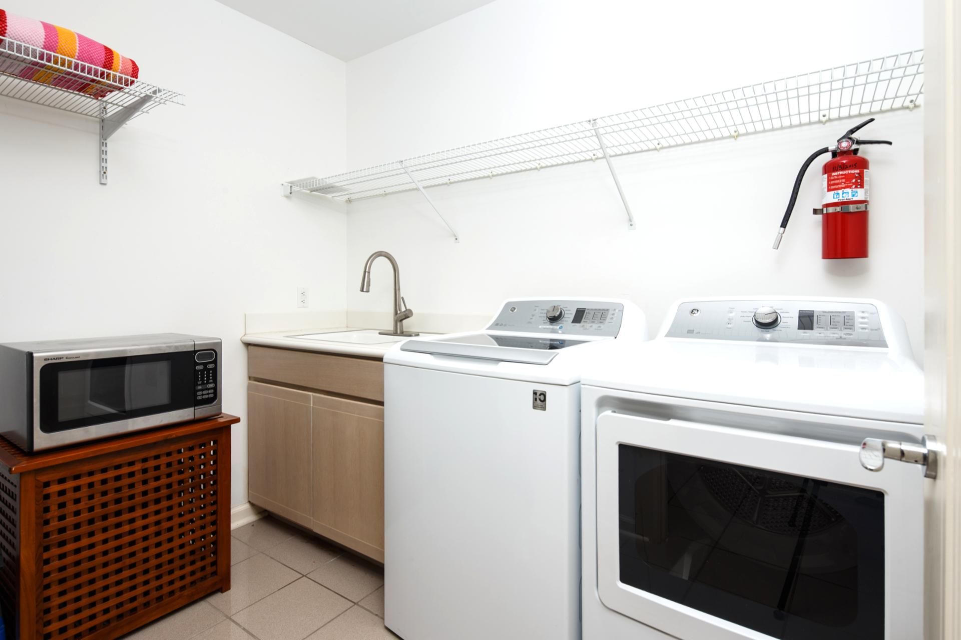 Une cuisine compacte équipée d’un four à micro-ondes, d’un évier et d’un lave-linge.