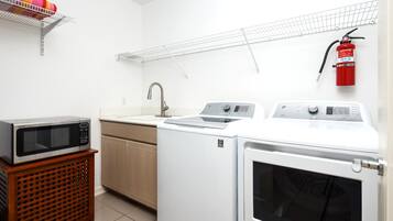 Una cocina compacta con microondas, lavabo y lavadora.