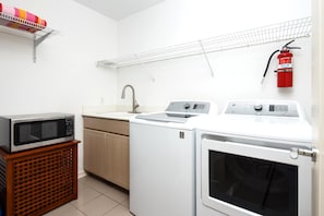 A compact kitchen with a microwave, sink, and washing machine. - Islands at Mauna Lani | Fairway View 2 BR | Car Incl. w/ 6+ Nights | IML-F3 by KBM (Waimea)