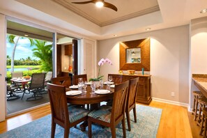 Comedor con una mesa grande dispuesta para seis personas, rodeado de sillas con asientos acolchados.
