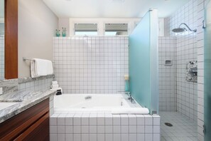 Uma casa de banho moderna com banheira, chuveiro e toucador com espelho.