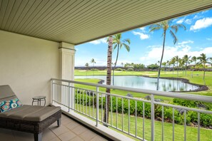 A balcony with a view of a golf course and a body of water.