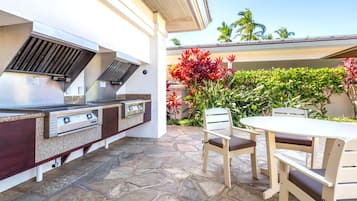 Une cuisine extérieure équipée d’un barbecue, d’une table et de chaises.