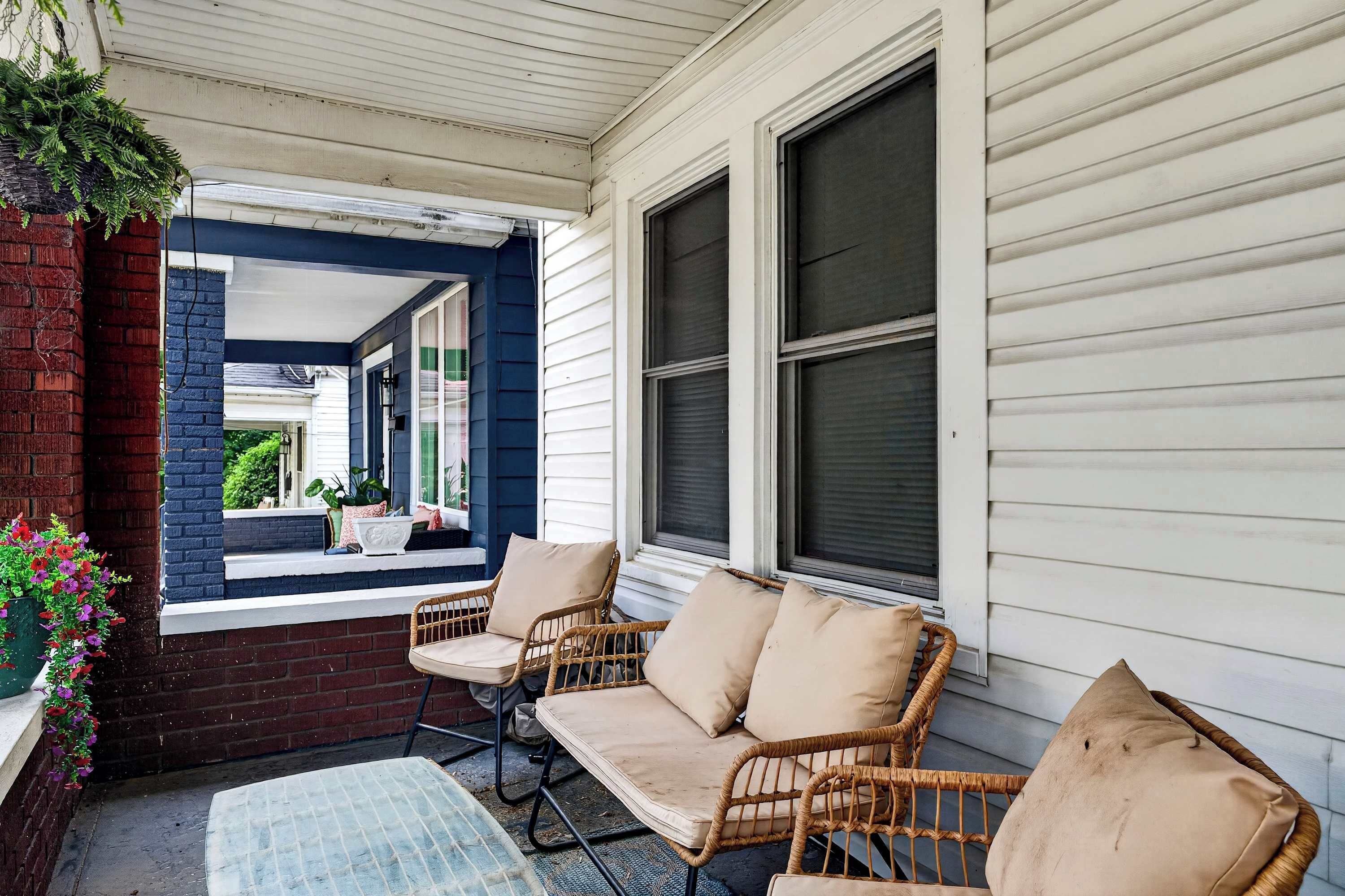 A covered porch with wicker furniture and a view of the street.