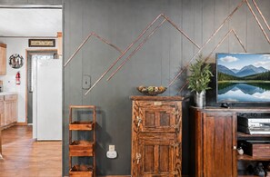 Ein Wohnzimmer mit Holzschrank, Fernseher und Wandregal.