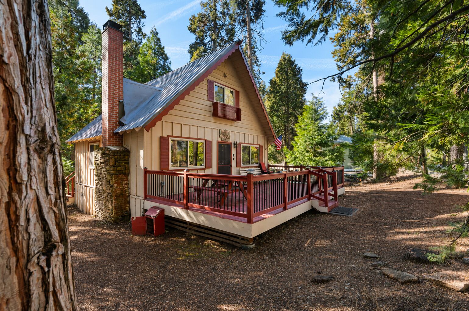 A cabin with a porch, surrounded by trees.