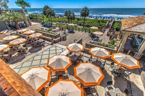An outdoor patio area with multiple tables and chairs, surrounded by orange umbrellas, overlooking a beach and ocean. - New Listing! Luxury Updated 4 BR 3 BA Golf View Near the Beach Pool Sea Pines (Hilton Head Island)