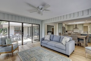 Un vaste espace de vie comprenant un canapé, une table basse et une table à manger avec des chaises. Une porte-fenêtre coulissante donne accès à un patio extérieur.