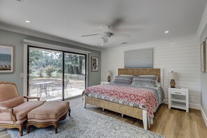 A bedroom with a bed, a chair, a nightstand, and a view of the outdoors. - New Listing! Luxury Updated 4 BR 3 BA Golf View Near the Beach Pool Sea Pines (Hilton Head Island)