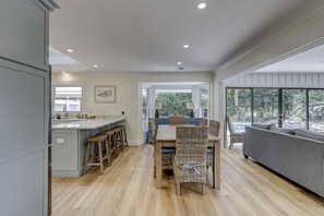 A modern kitchen with a central island, wooden stools, and a dining table. - New Listing! Luxury Updated 4 BR 3 BA Golf View Near the Beach Pool Sea Pines (Hilton Head Island)