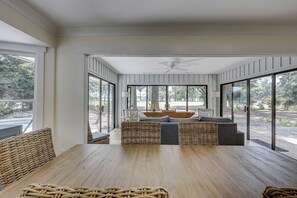 A spacious room with a large wooden table, wicker furniture, and a view of the outdoors through large windows. - New Listing! Luxury Updated 4 BR 3 BA Golf View Near the Beach Pool Sea Pines (Hilton Head Island)