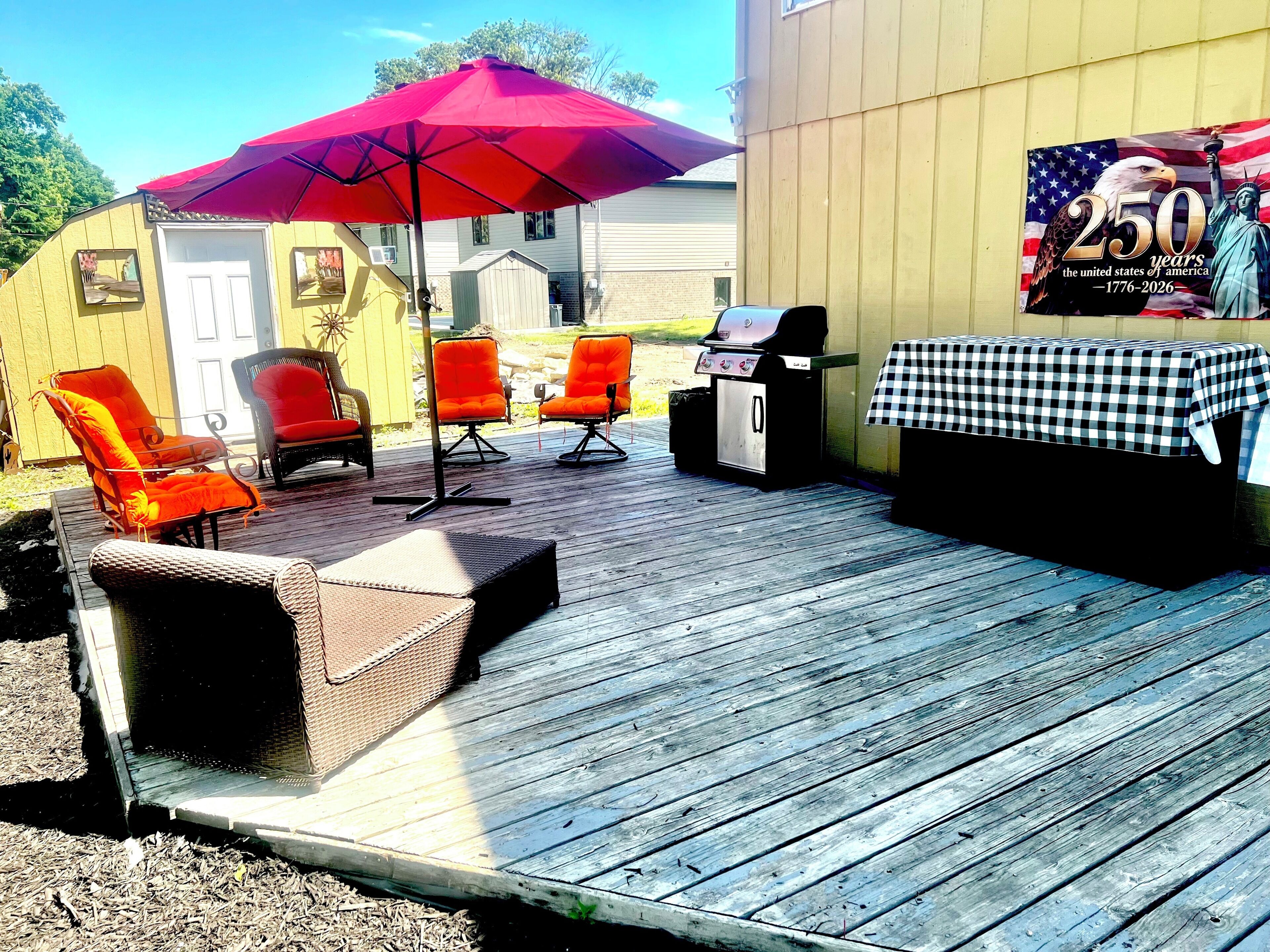 An outdoor patio with a grill, chairs, and a table.