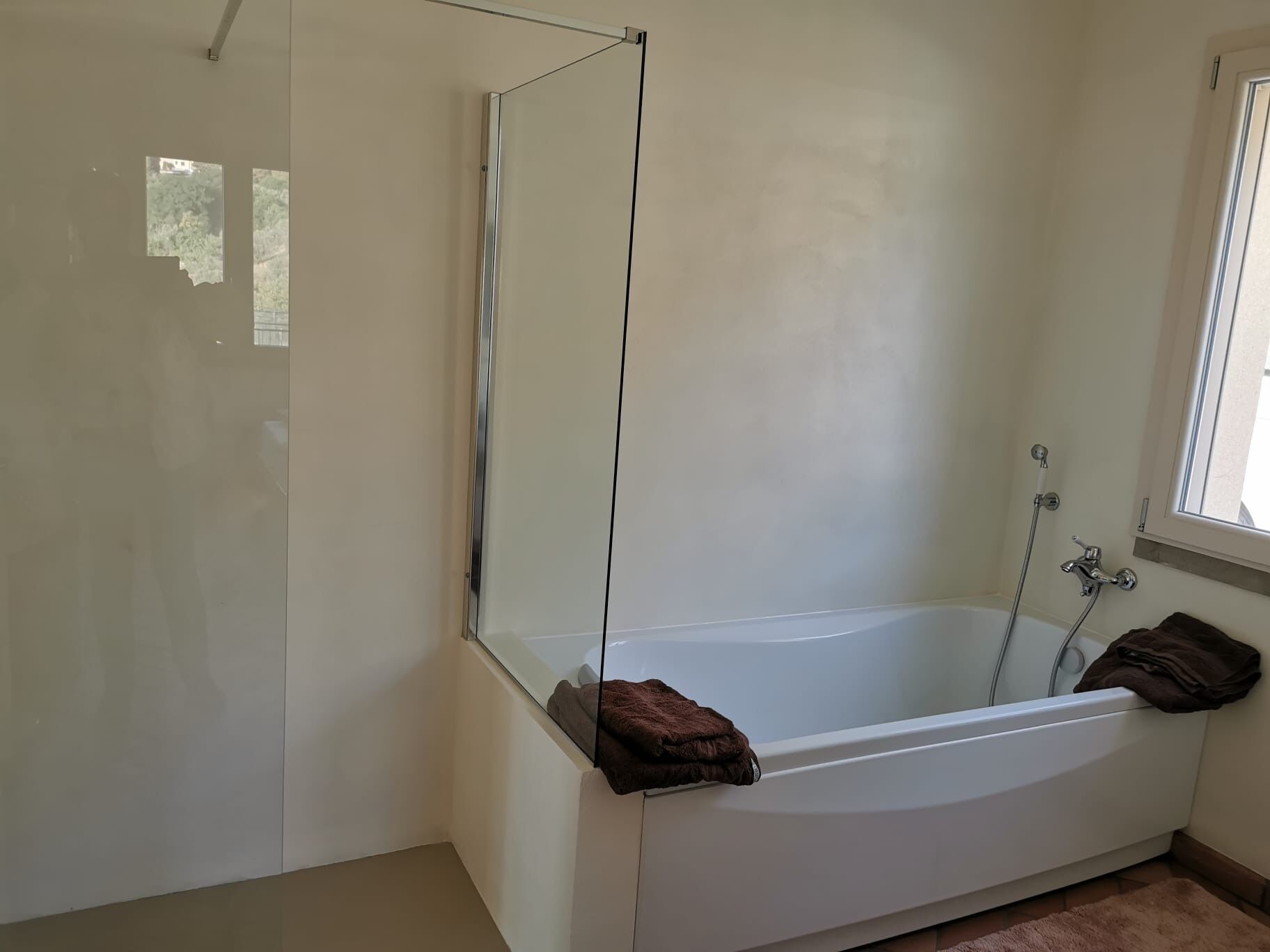 Un bagno con una vasca, una doccia e una finestra.