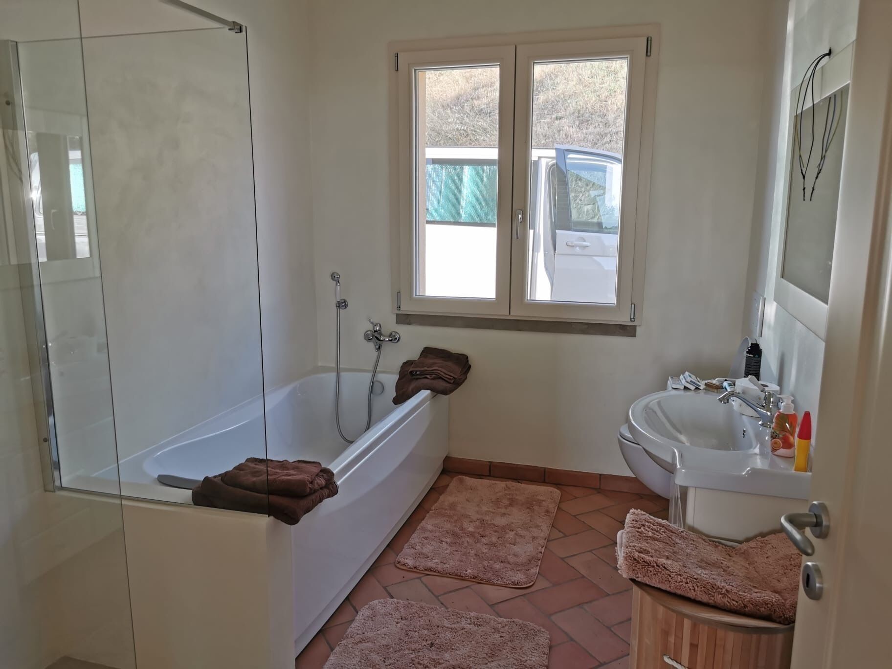 A bathroom with a bathtub, a shower, a sink, and a window.