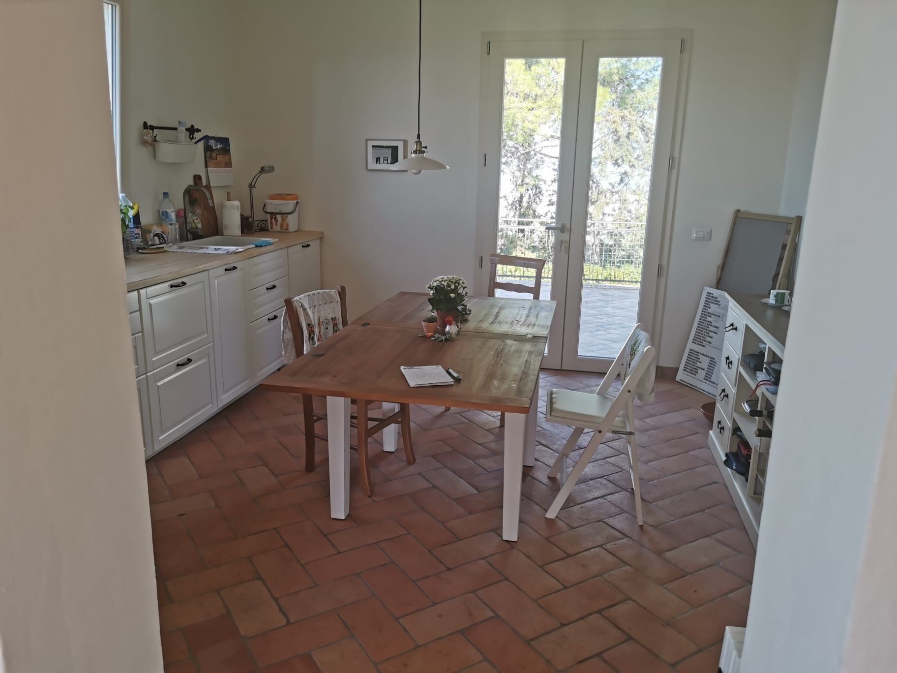 Une cuisine avec une table à manger, des chaises et une vue sur l’extérieur, visible à travers la porte vitrée.