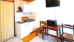 Una cucina compatta con forno a microonde, un piccolo frigorifero e un tavolo da pranzo in legno con sedie.
