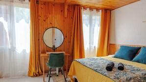 Una camera da letto con un letto, una scrivania, una sedia, uno specchio e tende.