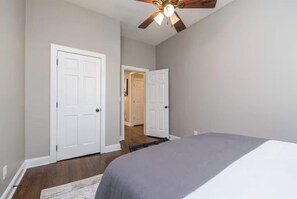 Una camera da letto con un letto, una ventola a soffitto e due porte bianche.