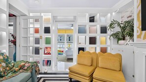 Una habitación con un sofá, un sillón amarillo, una estantería y una puerta que da a otra habitación.