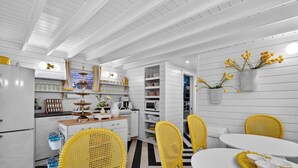 Una cocina moderna con armarios blancos, sillas de mimbre amarillas y una mesa de comedor con un mantel individual amarillo.