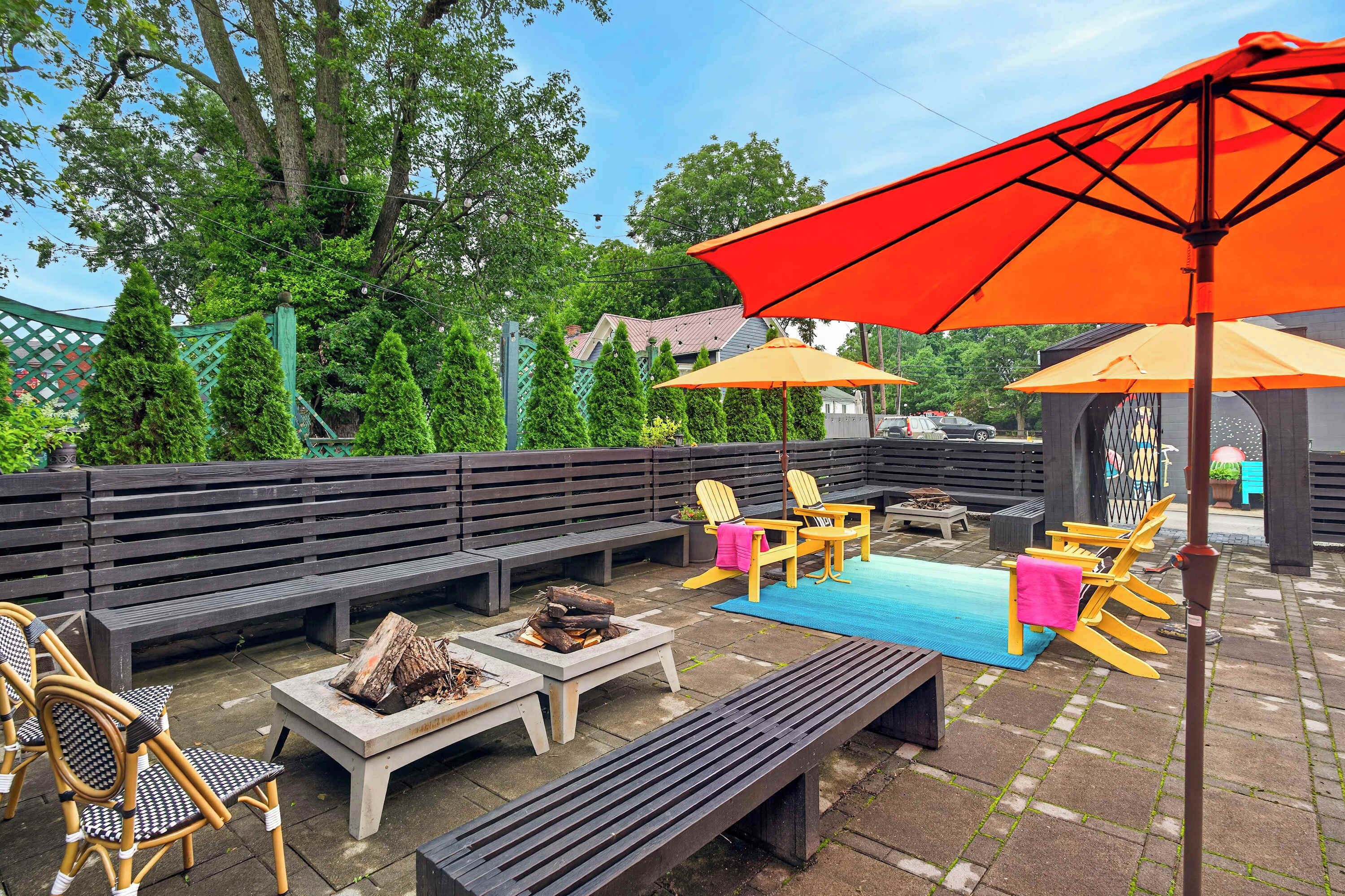 An outdoor patio with wooden benches, chairs, and a fire pit.